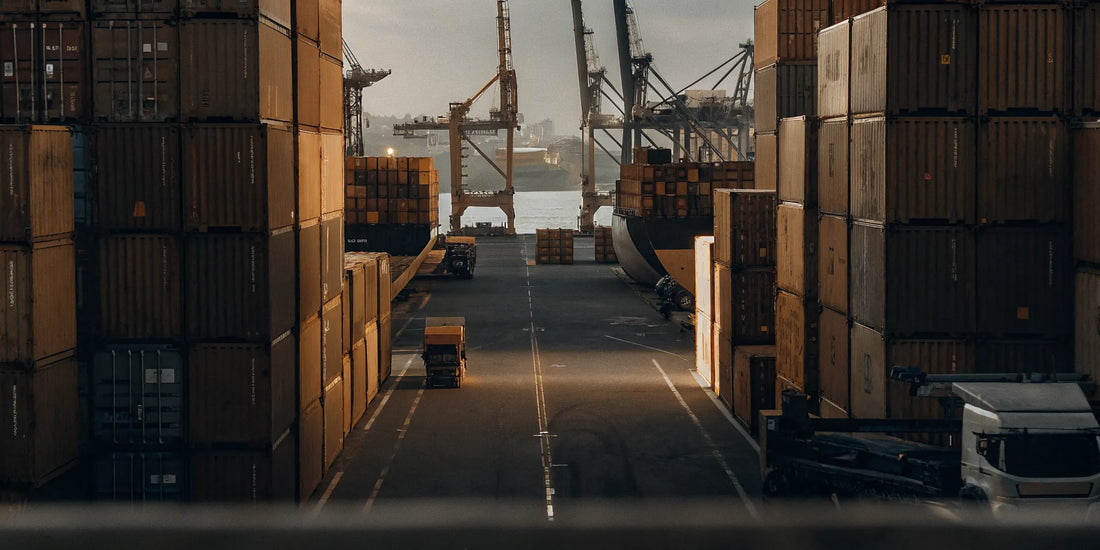Cargo shipping containers at a busy port with security seals visible on container doors