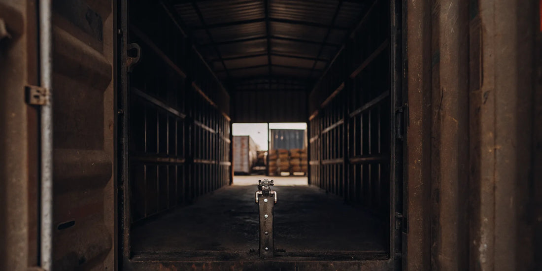 Shipping container secured with a heavy-duty padlock and high-security metal seal at a warehouse loading dock