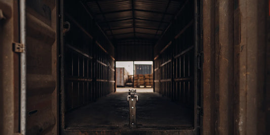 Shipping container secured with a heavy-duty padlock and high-security metal seal at a warehouse loading dock