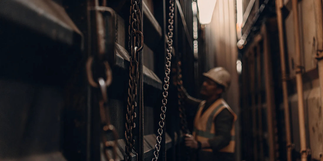 Industrial shipping containers in a logistics yard with a worker inspecting security seals on container door hardware
